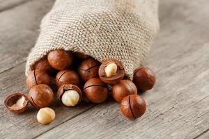 Macadamia nut on a wooden table in a bag, closeup, top view photo