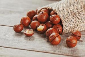 Macadamia nut on a wooden table in a bag, closeup, top view photo