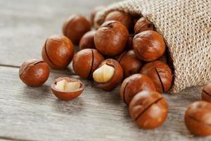 Macadamia nut on a wooden table in a bag, closeup, top view photo