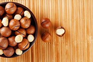 nuez de macadamia en textura de bambú, concepto de superalimentos y alimentos saludables foto