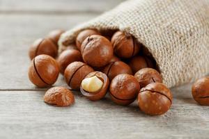 Macadamia nut on a wooden table in a bag, closeup, top view photo