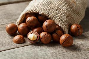 Macadamia nut on a wooden table in a bag, closeup, top view photo