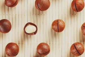 Flat composition with Australian macadamia nuts on bamboo light background. Patterns, repetitions photo