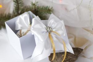 A Christmas gift decorated with a beautiful bow on a light background with a fir twig. Gifts, joy, surprise. Selective focus. the concept of Christmas and New Year. photo