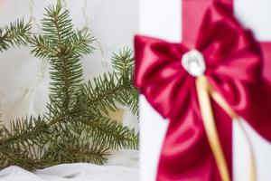 A Christmas gift decorated with a beautiful bow on a light background with a fir twig. Gifts, joy, surprise. Selective focus. the concept of Christmas and New Year photo