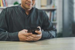 Crop picture of freelance man using smartphone on table, businessman using mobile phone to search or social media or shopping online or stock or crypto currency. Smart phone conversation conferrence. photo