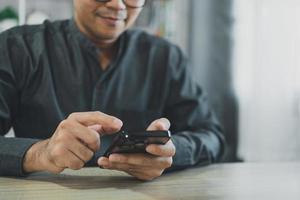Crop picture of freelance man using smartphone on table, businessman using mobile phone to search or social media or shopping online or stock or crypto currency. Smart phone conversation conferrence. photo