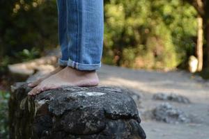 Someone wearing jean stand on the rock at the waterfall. photo