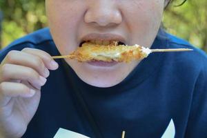Someone eating skewers fried chicken. photo