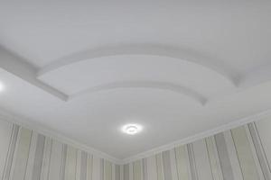 Detail of corner ceiling with intricate crown molding. Suspended ceiling and drywall construction in empty room in apartment or house. Stretch ceiling white and complex shape. photo