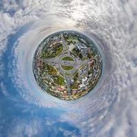 tiny planet in sky with clouds overlooking old town, urban development, historic buildings and crossroads. Transformation of spherical 360 panorama in abstract aerial view. photo