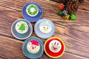 Christmas bakery concept. Cupcake with buttercream and topping, Santa Claus, Rudolf, and a Christmas tree on a wooden table. photo