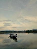 barco tradicional de madera flotando en las aguas del lago limboto, gorontalo, indonesia. pequeño bote de remos de madera en un lago tranquilo foto