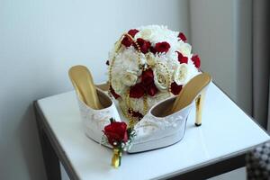 A pair of white women's high heels and a beautiful rose flower bucket. photo