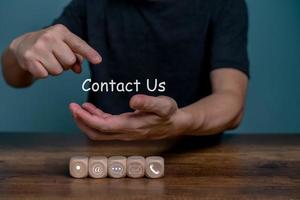 Hand holding and point on Contact Us for customer communication service with contact icon, E-mail, Phone number, Location, Social media group. photo