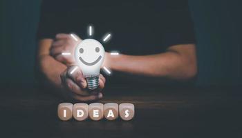 Hand of a man holding a light bulb with happy smiling face, The idea of inspiration, thinking, online technology, innovation ideas concept. photo