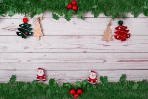 Christmas decoration with fir branches, christmas tree pendant, santa claus decoration and red berries on a wooden background photo