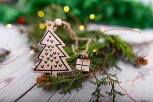 Craft gift wooden Christmas tree pendant on a background of bokeh Christmas garlands and christmas tree. Christmas tree decoration in the form of a Christmas tree close-up photo