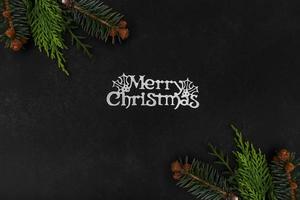 fondo oscuro de navidad o año nuevo con ramas de abeto, tablero negro de navidad enmarcado con decoraciones de temporada, casarse con texto de navidad, vista desde arriba. foto