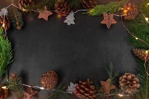 Christmas or New Year dark background with fir branches, Xmas black board framed with season decorations, space for text, view from above. photo