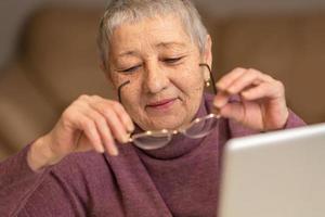 A senior woman sitting in front of a laptop communicates online through social networks. photo