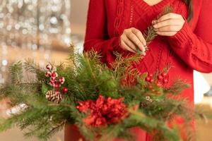 niña recoge un ramo navideño de ramas de abeto, flores y adornos de árboles de navidad foto