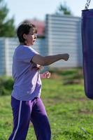 Girl punching sandbag. Muaythai boxing training. Healthy girl punching at boxing bag. Concept of boxing training, exercising, working out at fitness, sport photo