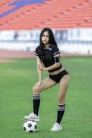 joven y hermosa mujer asiática viste a un jugador de fútbol animando el deporte, las hinchas femeninas animan el juego de fútbol foto