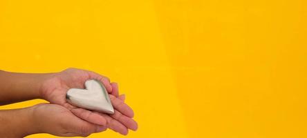 hands holding heart with yellow background photo