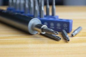 Picture of a mini electric screwdriver, interchangeable tip, placed on a wooden floor. photo