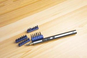 Picture of a mini electric screwdriver, interchangeable tip, placed on a wooden floor. photo