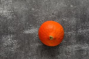 Small ripe orange pumpkin on a stone rustic background photo