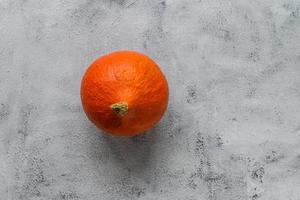 pequeña calabaza naranja madura sobre fondo rústico gris foto
