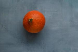 pequeña calabaza naranja madura sobre un fondo rústico burdeos foto