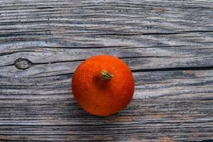 pequeña calabaza naranja madura sobre un fondo rústico de madera foto