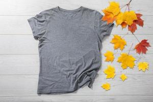 Grey shirt mockup - tshirt with autumn leaves on white wooden desk photo