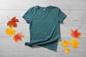 Green shirt mockup - tshirt with autumn leaves on white wooden desk photo