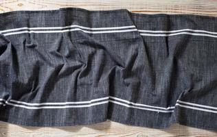 Blue tablecloth, napkin, rough fabric texture with creased folds on wooden desk top view. photo