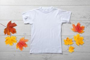 Front views of little boy in white t-shirt on white wooden background. Mockup for design photo