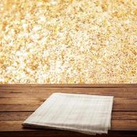 Empty canvas napkin on wooden desk top view. Festive sparkling gold background. photo