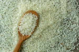 dry rice or uncooked rice. top angle view of raw rice and wooden spoon photo