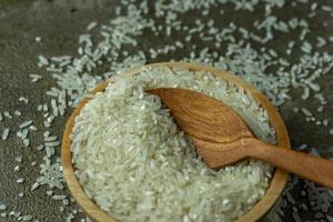 uncooked rice or dry rice. raw rice in wooden bowl with wooden spoon and fork photo