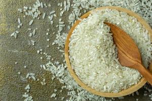 uncooked rice or dry rice. raw rice in wooden bowl with wooden spoon and fork photo