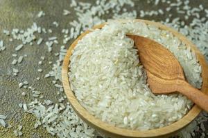 uncooked rice or dry rice. raw rice in wooden bowl with wooden spoon and fork photo