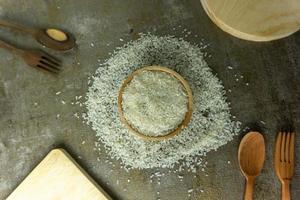uncooked rice or dry rice. raw rice in wooden bowl with wooden spoon and fork photo