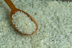 dry rice or uncooked rice. top angle view of raw rice and wooden spoon photo