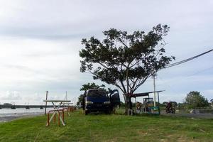 concepto de cafetería móvil. silla y mesa frente a la autocaravana. concepto de picnic. autocaravana estacionada debajo del árbol y al lado del río. foto