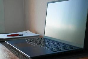 blank laptop screen and office supplies photo