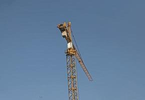 Construction crane against the blue sky. The real estate industry. A crane uses lifting equipment at a construction site. photo