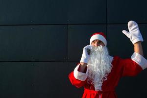 Modern Santa Claus talking on the phone. Ordering the services of an animator for the Christmas and new year. Online greetings via the Internet and mobile communication, social distance photo